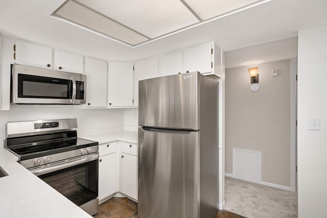 kitchen with white cabinets, appliances with stainless steel finishes, and dark colored carpet