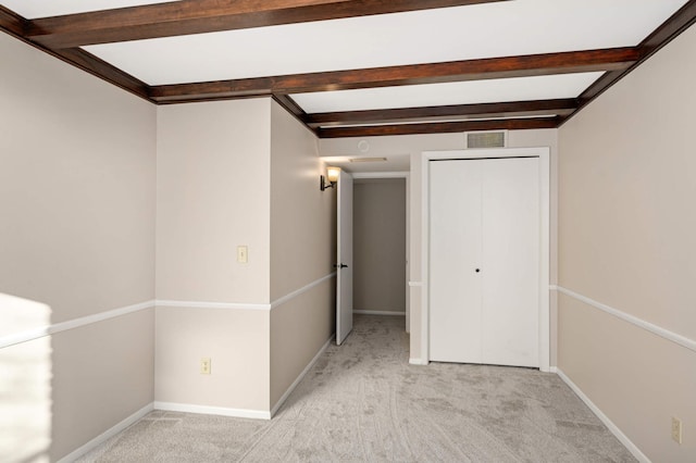 interior space featuring light colored carpet and beamed ceiling