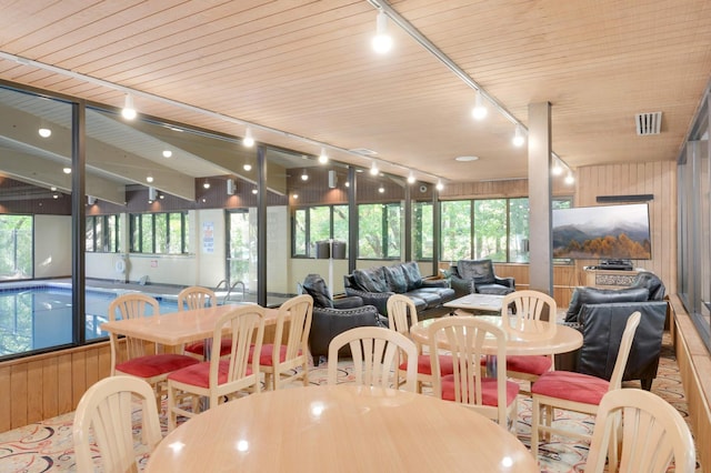 dining space featuring wood ceiling and wood walls