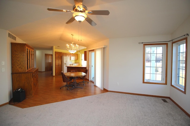 unfurnished dining area with carpet flooring, lofted ceiling, and ceiling fan with notable chandelier