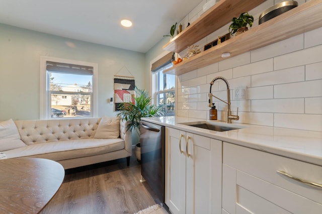 kitchen featuring dishwasher, sink, hardwood / wood-style flooring, decorative backsplash, and white cabinetry