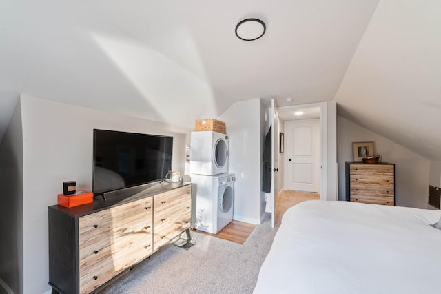 bedroom with stacked washer and dryer, lofted ceiling, and light colored carpet