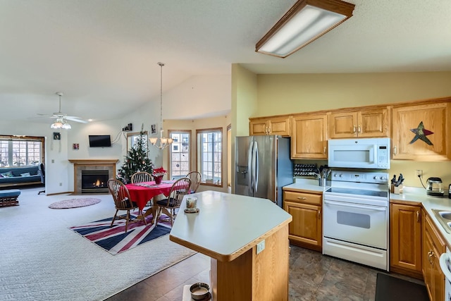 kitchen with hanging light fixtures, lofted ceiling, white appliances, a kitchen island, and ceiling fan with notable chandelier