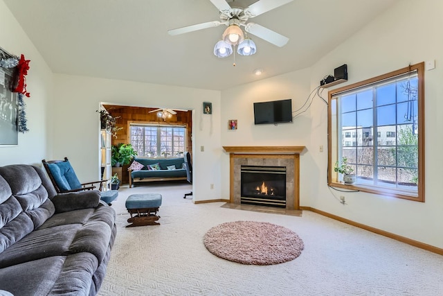 carpeted living area with ceiling fan, baseboards, and a tiled fireplace