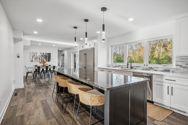 kitchen featuring pendant lighting, a center island, white cabinets, sink, and appliances with stainless steel finishes