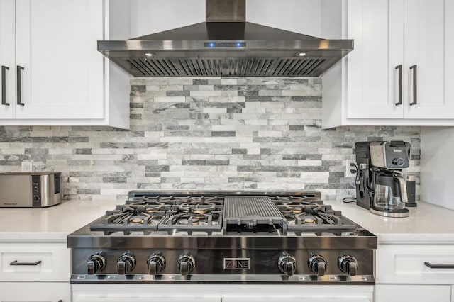 kitchen featuring tasteful backsplash, white cabinetry, wall chimney range hood, and stainless steel gas stovetop