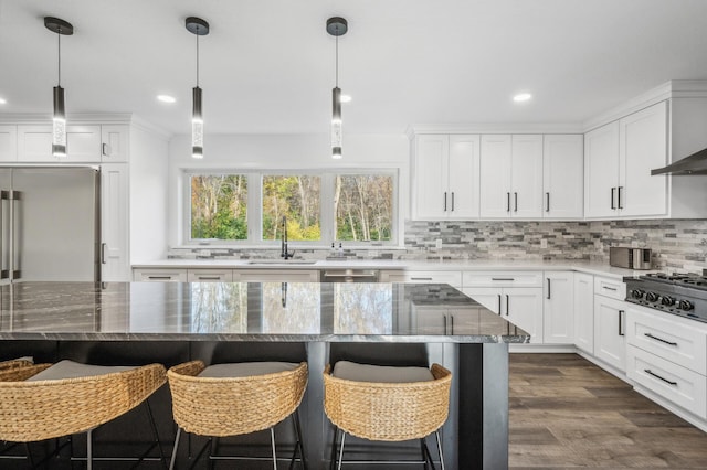 kitchen featuring a kitchen bar, appliances with stainless steel finishes, sink, white cabinets, and a center island