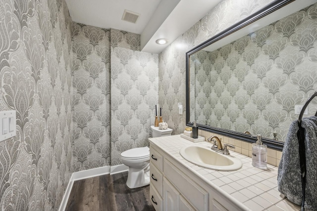 bathroom with toilet, vanity, and hardwood / wood-style flooring