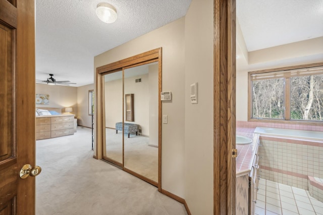 corridor with light carpet, sink, and a textured ceiling