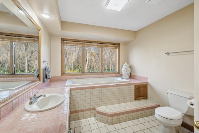 bathroom with tile patterned flooring, sink, toilet, and tiled tub