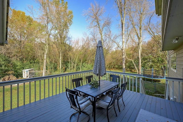 wooden terrace with a lawn and a trampoline