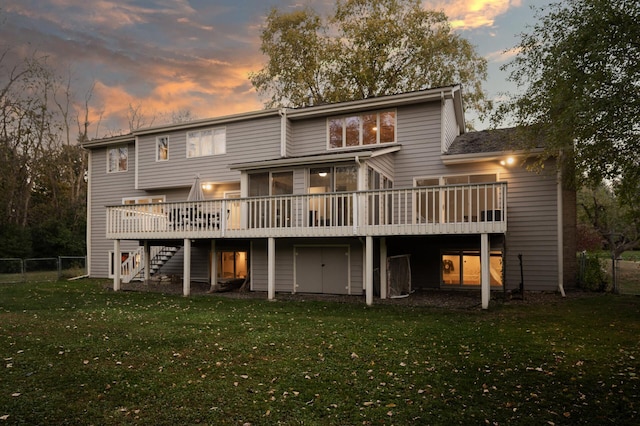 back house at dusk with a lawn, a wooden deck, and a sunroom