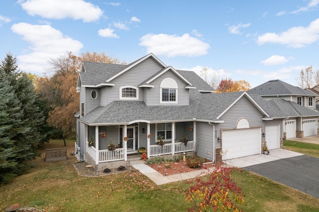 view of front of house featuring covered porch, a garage, and a front lawn