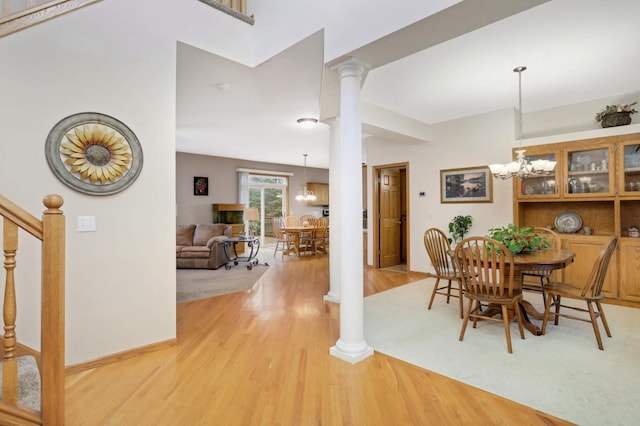 dining area featuring light hardwood / wood-style flooring, ornate columns, and a notable chandelier