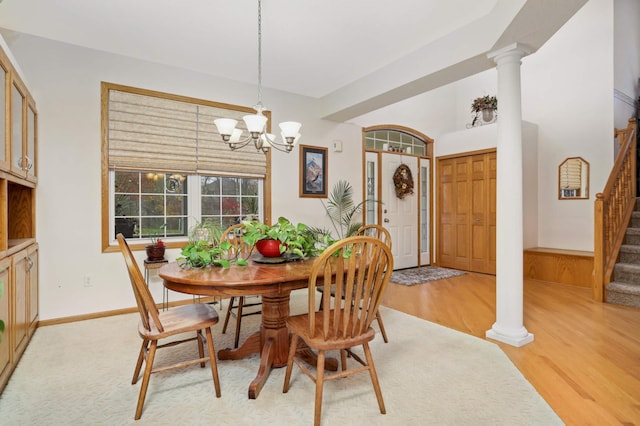 dining room featuring light wood-type flooring, decorative columns, and an inviting chandelier