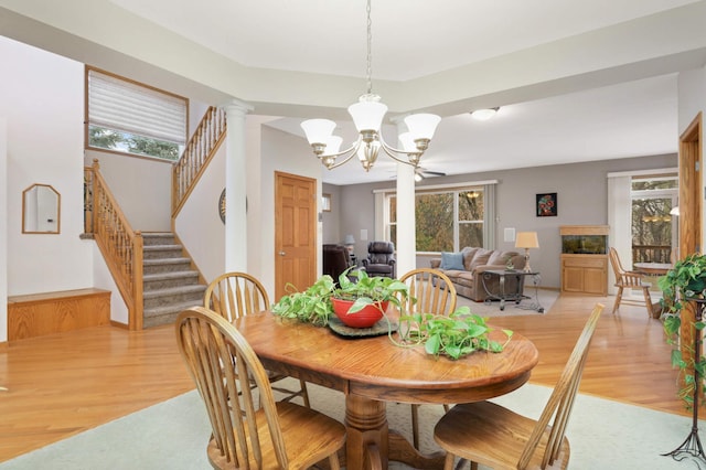 dining area with light wood-type flooring, decorative columns, and a notable chandelier