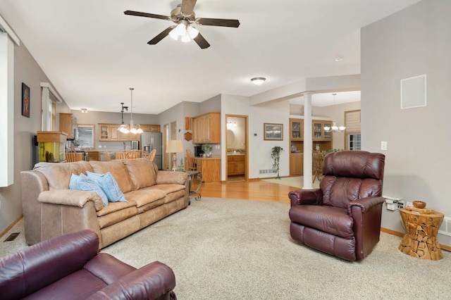 living room with ceiling fan with notable chandelier, light carpet, and decorative columns