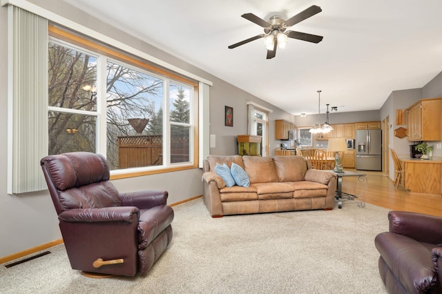 carpeted living room with ceiling fan with notable chandelier