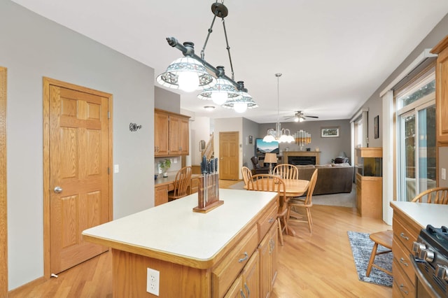 kitchen with a center island, stainless steel stove, light hardwood / wood-style flooring, and ceiling fan