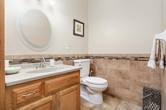 bathroom featuring tile patterned flooring, vanity, tile walls, and toilet