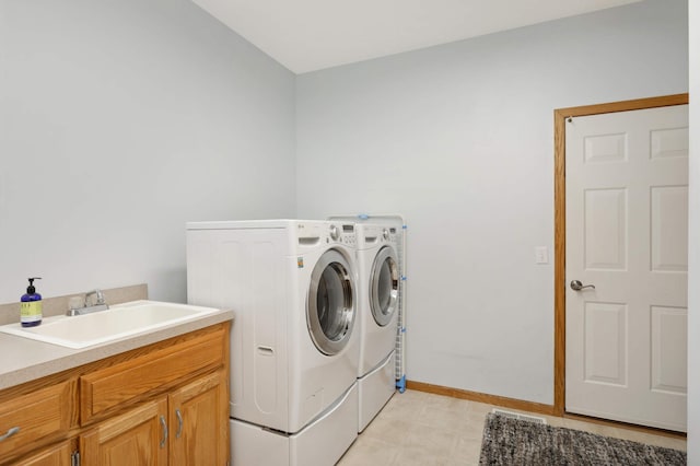 clothes washing area with separate washer and dryer, sink, and cabinets