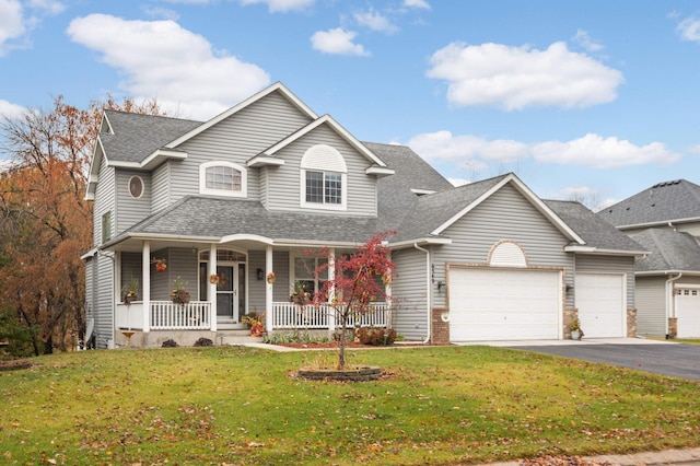 view of front of home with covered porch, a garage, and a front yard