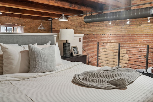 bedroom with beam ceiling and brick wall