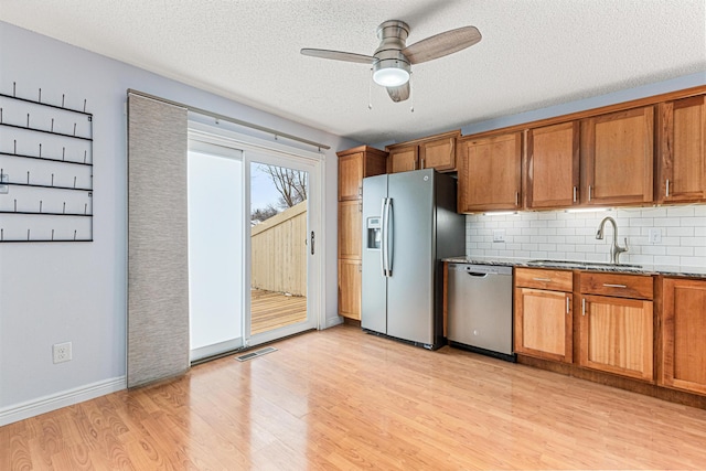 kitchen featuring sink, light hardwood / wood-style floors, a textured ceiling, and appliances with stainless steel finishes