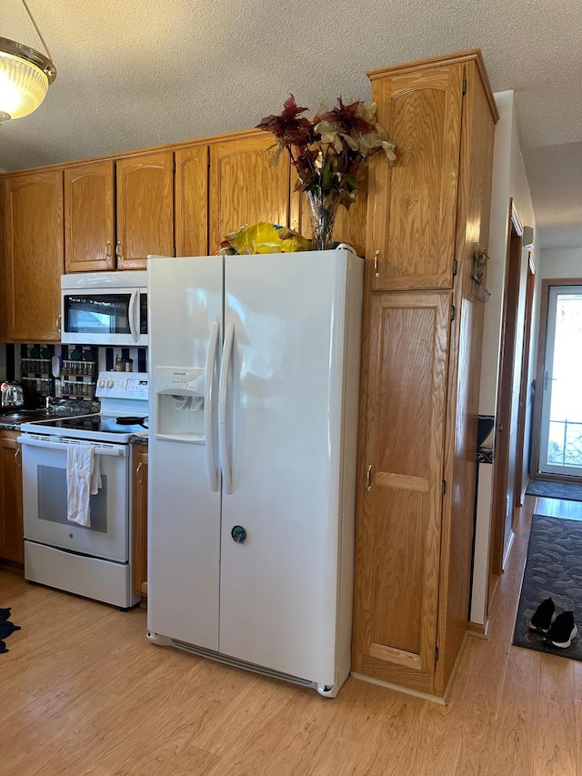 kitchen featuring a textured ceiling, backsplash, light hardwood / wood-style flooring, and white appliances