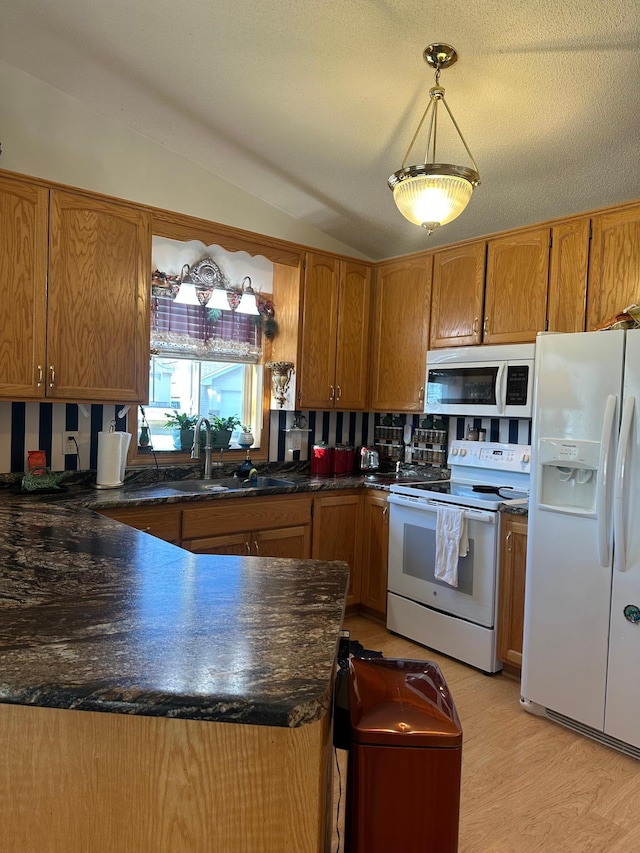 kitchen with kitchen peninsula, white appliances, sink, pendant lighting, and lofted ceiling