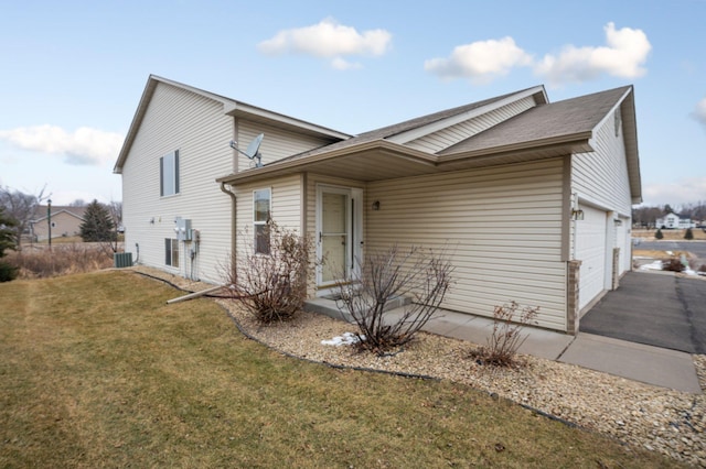 exterior space with a garage, a front yard, and central AC