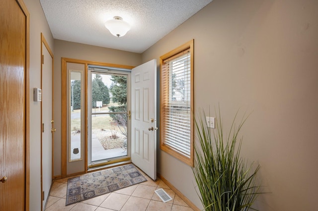 foyer entrance featuring light tile patterned flooring and a textured ceiling