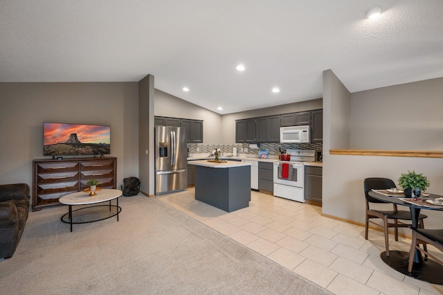 kitchen featuring decorative backsplash, white appliances, a kitchen island, lofted ceiling, and light tile patterned flooring