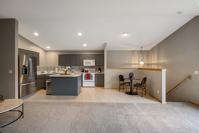 kitchen with white appliances, hanging light fixtures, vaulted ceiling, tasteful backsplash, and a kitchen island