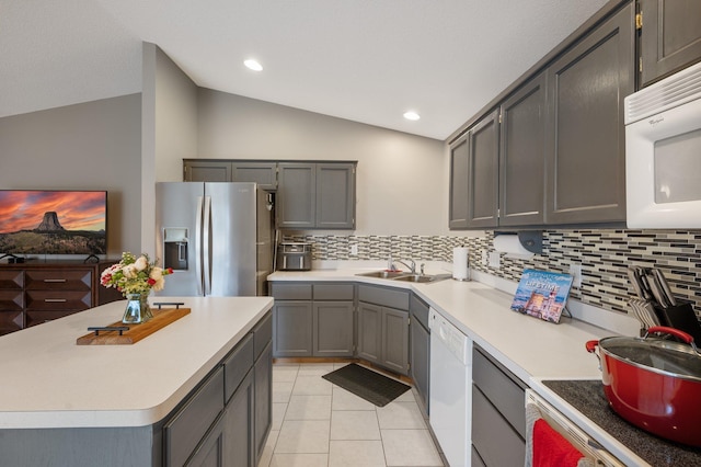 kitchen featuring vaulted ceiling, gray cabinets, tasteful backsplash, and white appliances