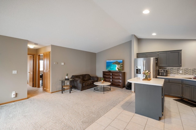 living room with sink, light tile patterned floors, and vaulted ceiling