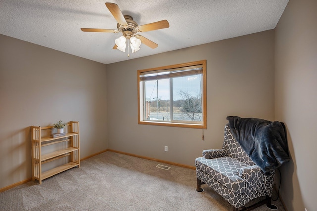 living area with light carpet, ceiling fan, and a textured ceiling