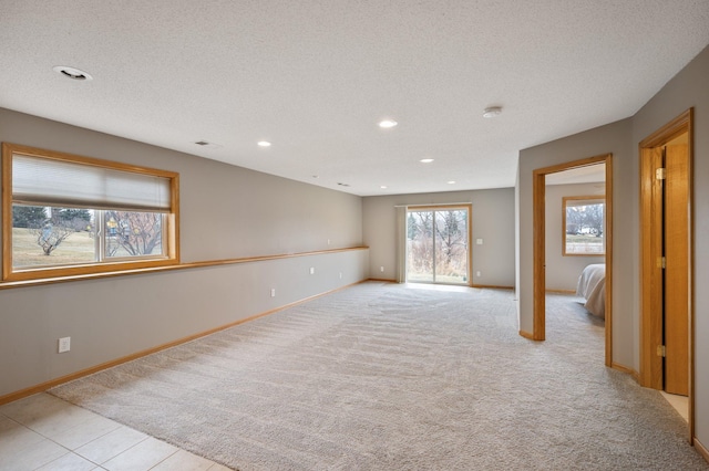 spare room with light colored carpet and a textured ceiling