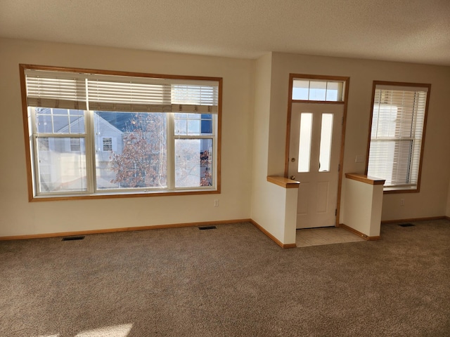 entryway with a textured ceiling and light colored carpet