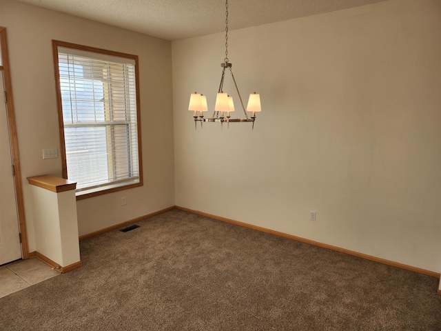 unfurnished room with a textured ceiling, light colored carpet, and a notable chandelier