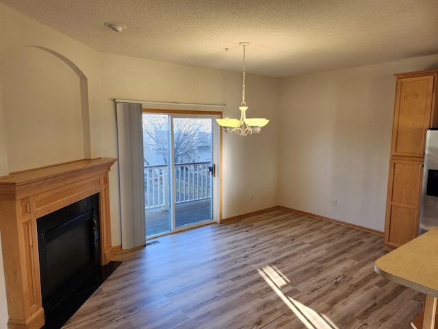 unfurnished living room with hardwood / wood-style floors, a textured ceiling, and a notable chandelier