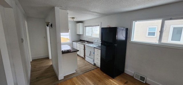 kitchen with white cabinetry, sink, white electric range oven, black fridge, and light wood-type flooring