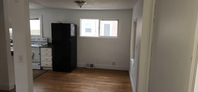 interior space featuring black refrigerator, hardwood / wood-style floors, and a textured ceiling