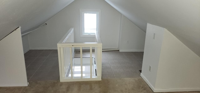 additional living space with dark tile patterned flooring and vaulted ceiling