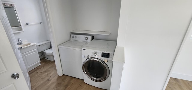 washroom with washing machine and clothes dryer, light hardwood / wood-style flooring, and sink