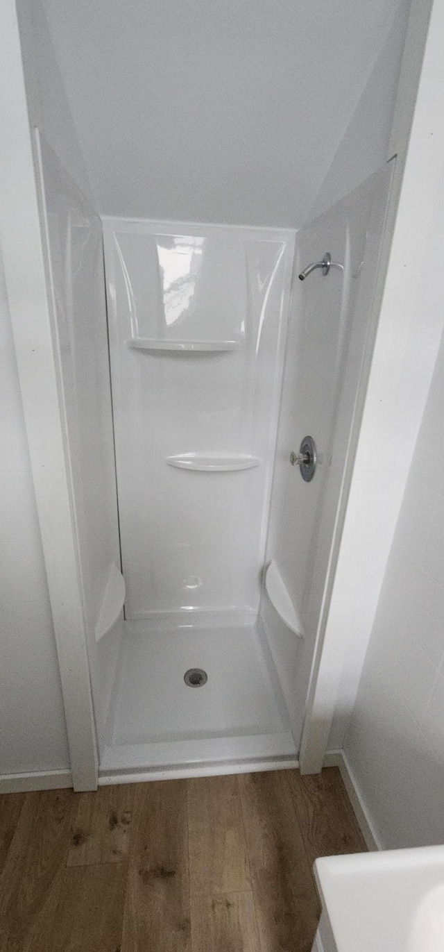 bathroom with a shower, hardwood / wood-style flooring, and lofted ceiling