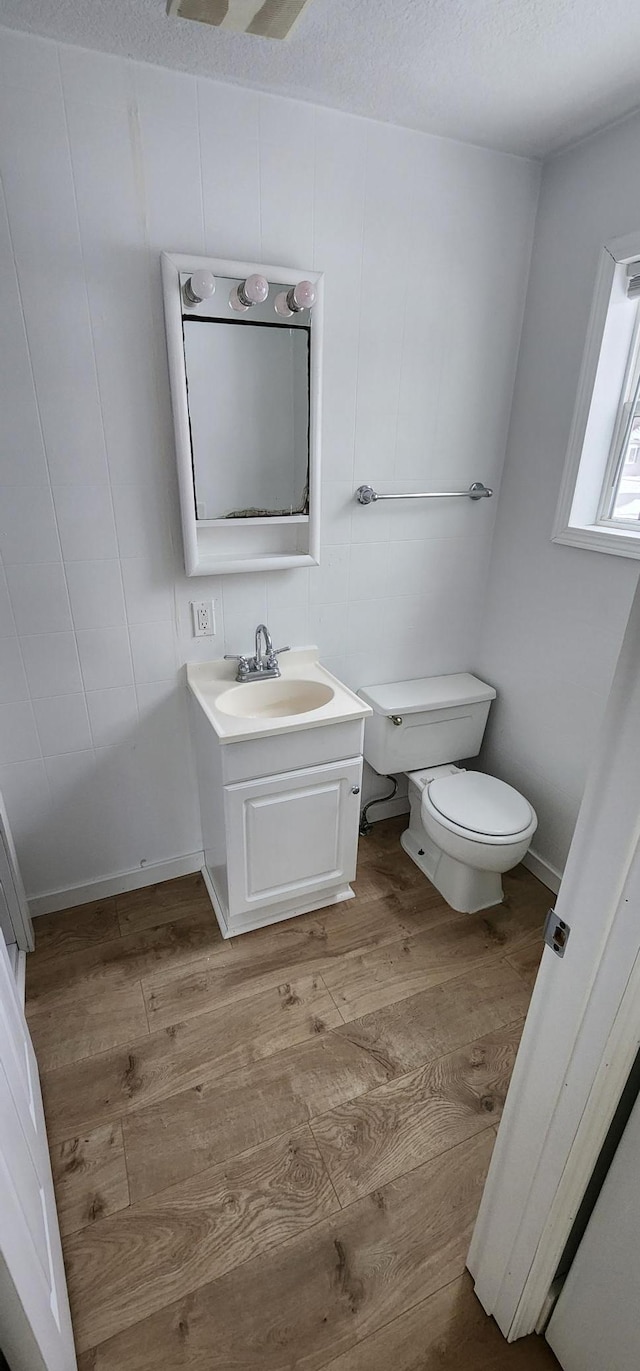 bathroom with toilet, vanity, a textured ceiling, and hardwood / wood-style flooring