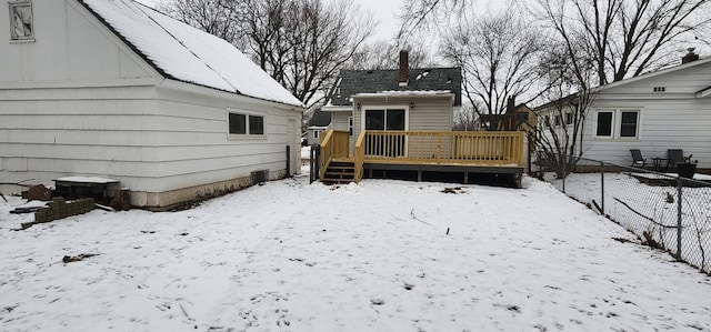 snow covered rear of property with a deck