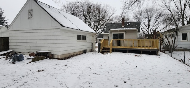 snow covered back of property with a wooden deck