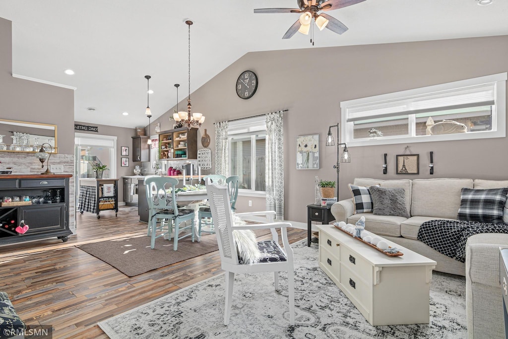 living room with ceiling fan with notable chandelier, light hardwood / wood-style floors, and lofted ceiling